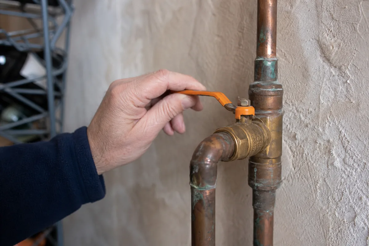 Vanne d&rsquo;arrêt général en laiton sur une arrivée d&rsquo;eau en cuivre, dans un cellier de maison ancienne