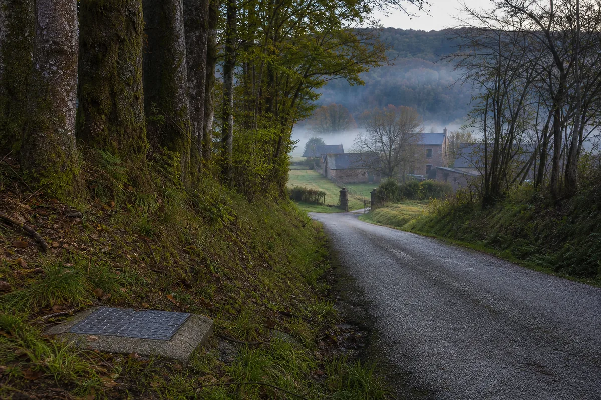 Chemin de campagne menant à un hameau de granit dans la vallée de l&rsquo;Ellé, portail ouvert en fin de journée